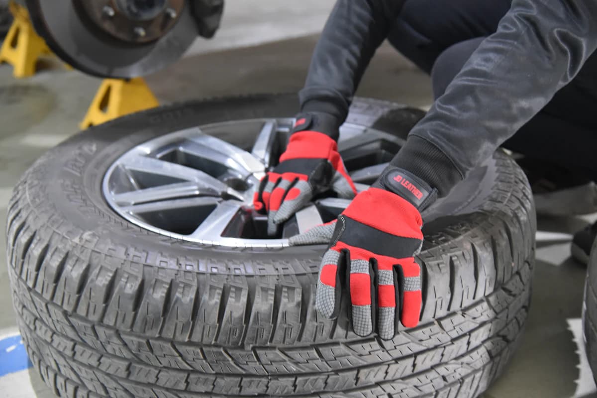 Tyre fitter in work gloves fitting a wheel and tyre